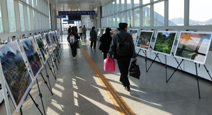 영천역 승강장 입출구 통로에 전시된 제17회 영천관광 전국사진공모전 입상작품을 철도 이용객들이 관람하고 있다.